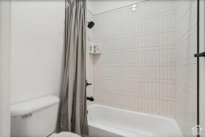 Bathtub with white subway tile surround, matte black shower fixtures, and an integrated corner shelf