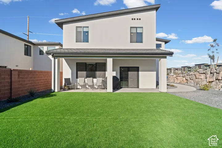 Spacious artificial turf lawn, covered patio, and large glass sliding door access