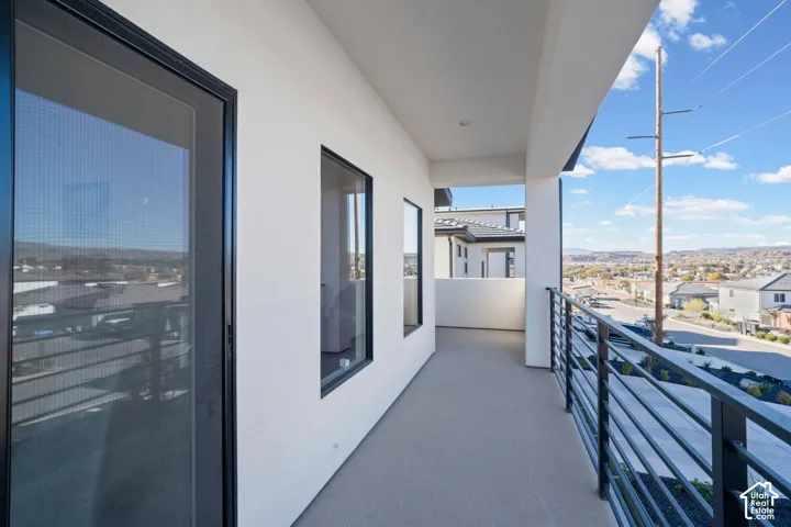 Exterior balcony featuring a concrete surface, black metal railing, and recessed lighting
