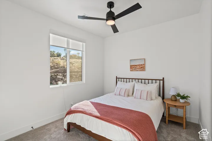 White walls with a window, modern ceiling fan, and carpeted flooring
