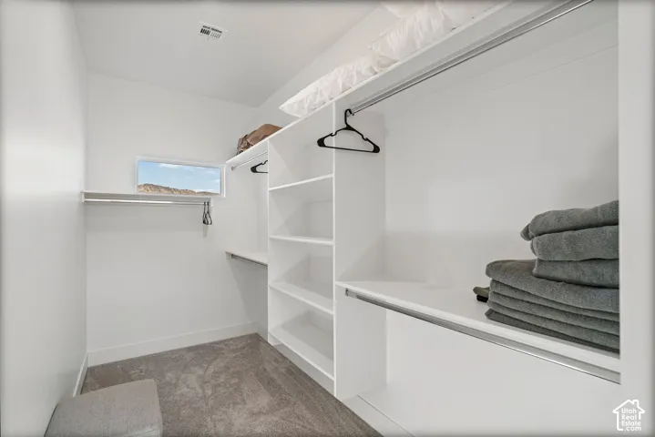 Spacious closet featuring built-in shelving, hanging rods, and a window providing natural light