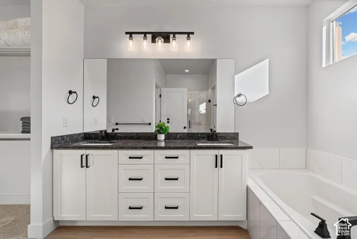 Dual vanity with white cabinetry, dark countertop, and black fixtures