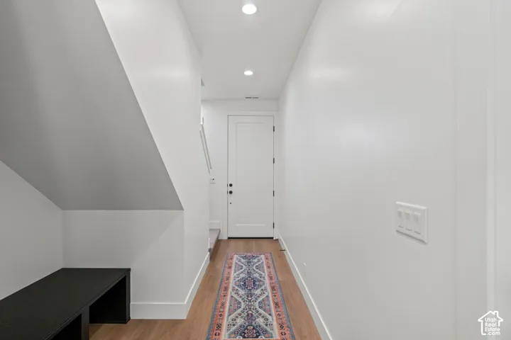 Recessed lighting illuminates the hallway with wood-finish flooring