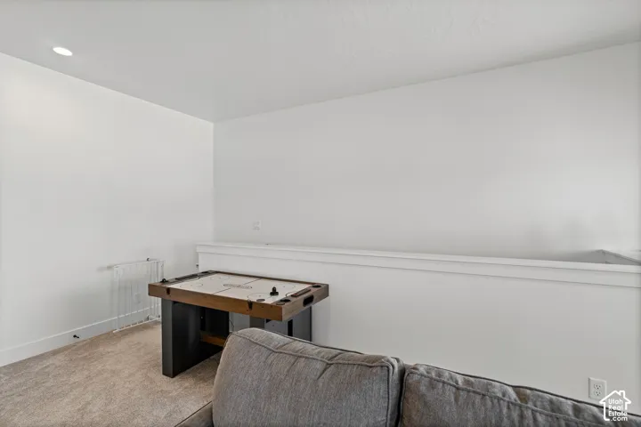 Carpeted flooring, recessed ceiling lighting, and a white wall with a white half-wall partition