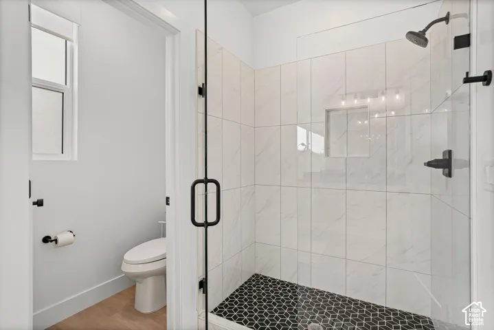 Glass-enclosed shower with a black geometric tile floor and white subway tile walls