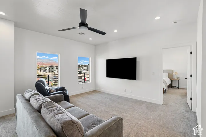 Recessed lighting, modern ceiling fan, wall-mounted television, and neutral carpeting