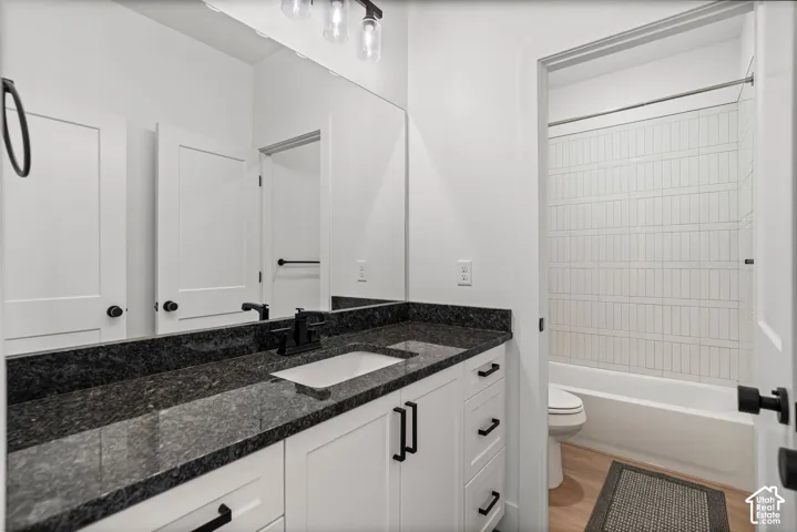 Vanity with a dark granite countertop, integrated rectangular sink, and matte black faucet