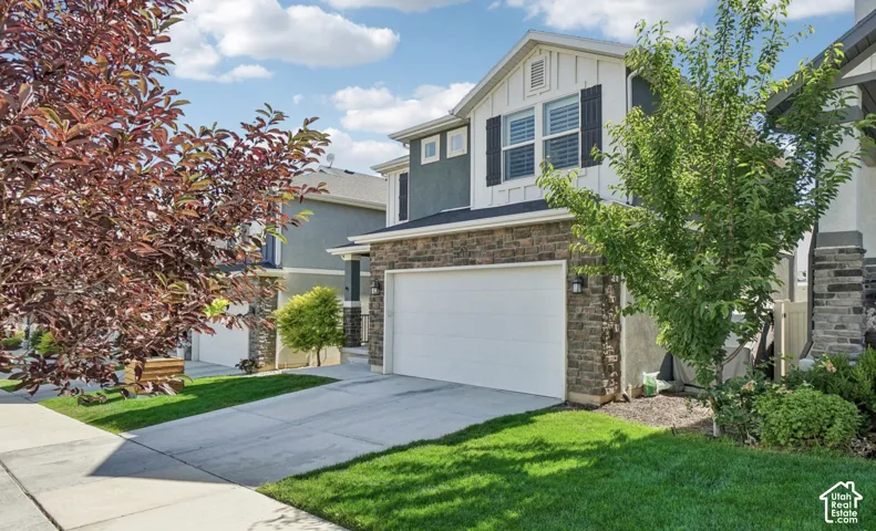 Stone facade, stucco exterior, two-car garage, mature landscaping, and concrete driveway