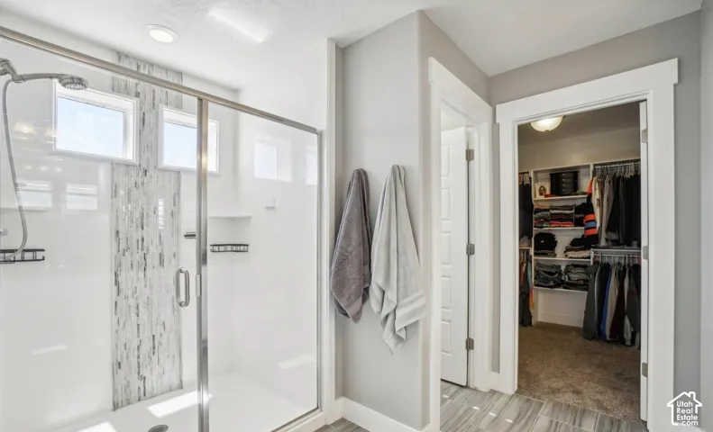 Glass-enclosed shower with a tiled accent wall and built-in shelving