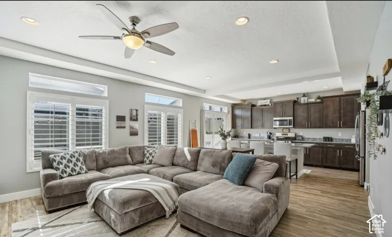 Open-concept living area with wood-finish flooring, recessed lighting, and a ceiling fan