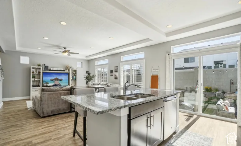 Open-concept living space featuring wood-finish flooring, recessed lighting, and tray ceilings