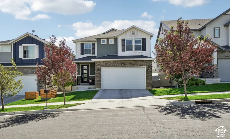 Two-story residence featuring a stone and stucco exterior, an attached two-car garage, and a landscaped front yard