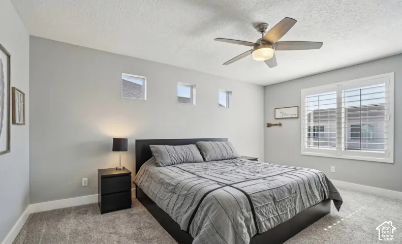 Recessed ceiling fan with integrated lighting, multiple transom windows, large window with louvered shutters, carpeted flooring, and neutral wall tones