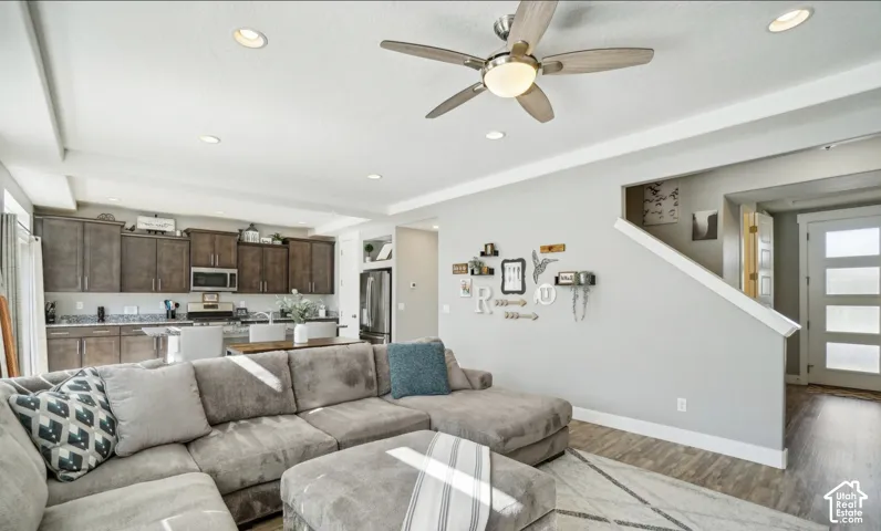 Recessed ceiling lighting, wood-finish flooring, a ceiling fan, dark wood cabinetry, and a multi-panel door
