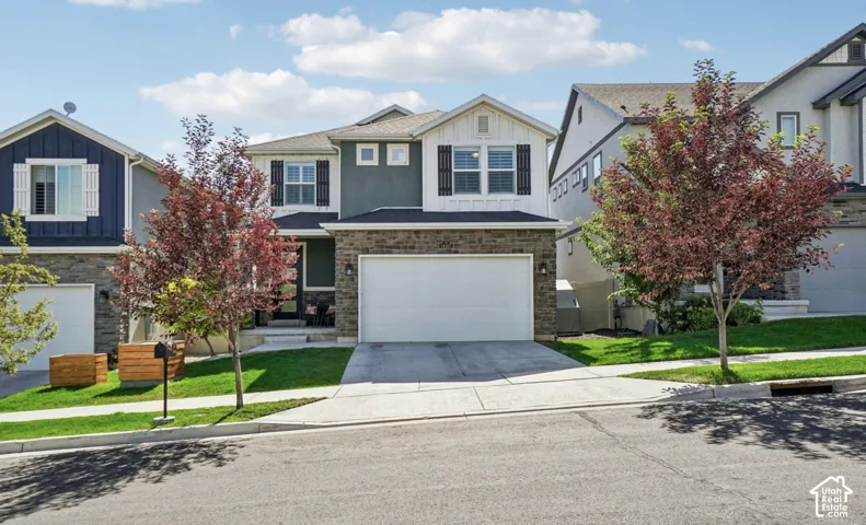 Modern two-story residence with a two-car garage, stone and stucco exterior, and a covered front entry