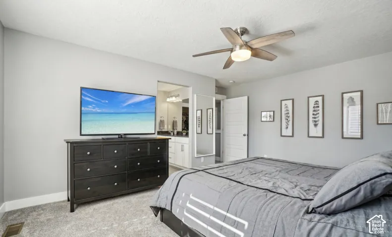 Light gray wall tones, ceiling fan with integrated lighting, textured carpeting, and white paneled door