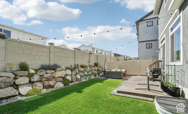 Manicured lawn, rock garden, concrete patio, privacy fencing, and string lights
