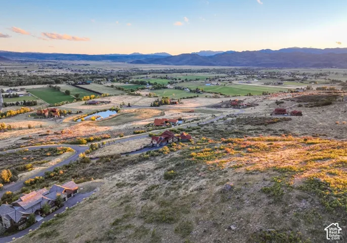 Expansive rural landscape featuring distant mountains and scattered residential properties with visible driveways