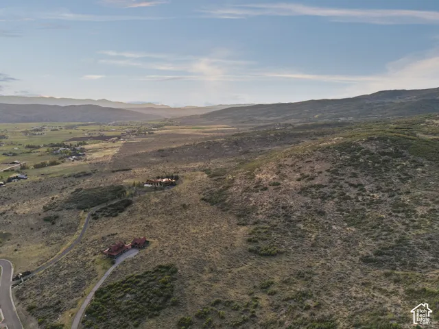Expansive mountainous terrain with multiple residences and a paved access road