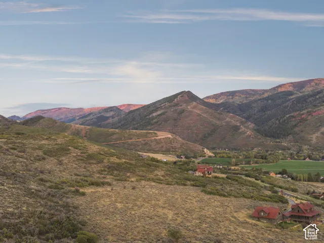 Expansive property featuring mountainous terrain, distant valley, and multiple structures with red roofs