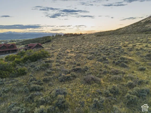 Expansive property with a sloping terrain, natural ground cover, and distant mountain range