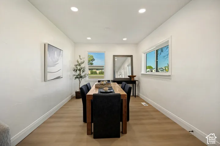 Dedicated dining room with wood-finish flooring, recessed ceiling lighting, and multiple windows framing natural light throughout the space