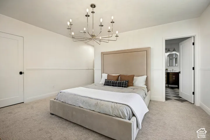 Light-toned carpeted flooring, decorative wall molding, and a modern chandelier