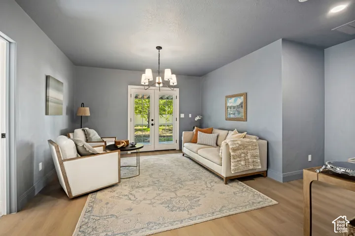 Spacious room with wood-finish flooring, French doors, and a multi-light chandelier