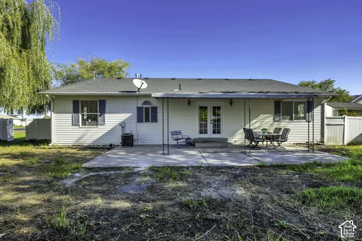 Rear exterior featuring white siding, a covered concrete patio, and double French doors