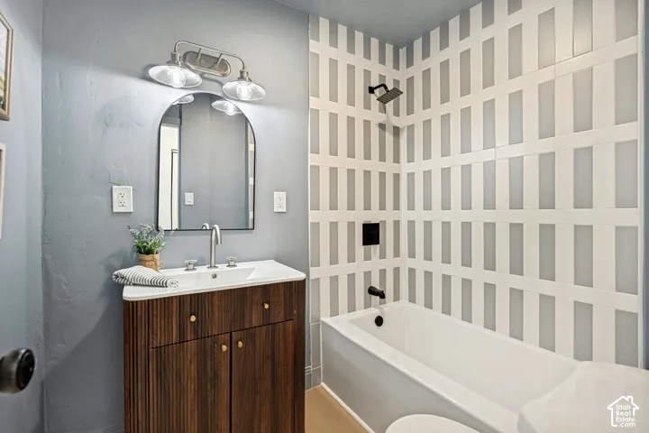 Bathroom featuring a wood-finish vanity with an integrated sink, an arched mirror, and a modern light fixture