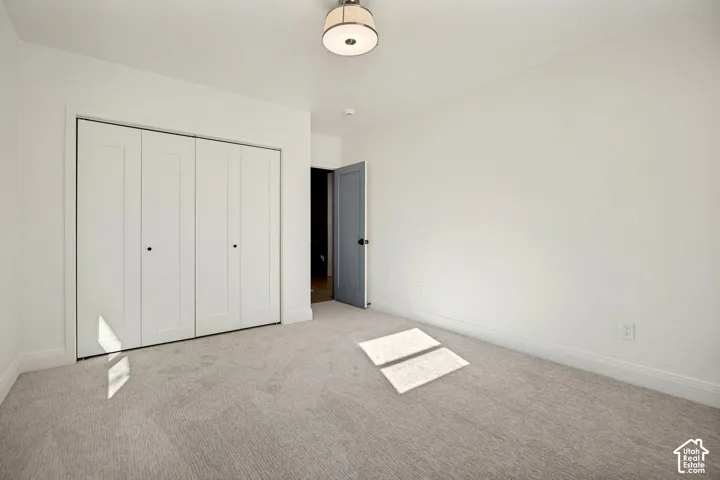 Recessed bi-fold closet doors, light-toned carpeting, and a flush mount ceiling light fixture