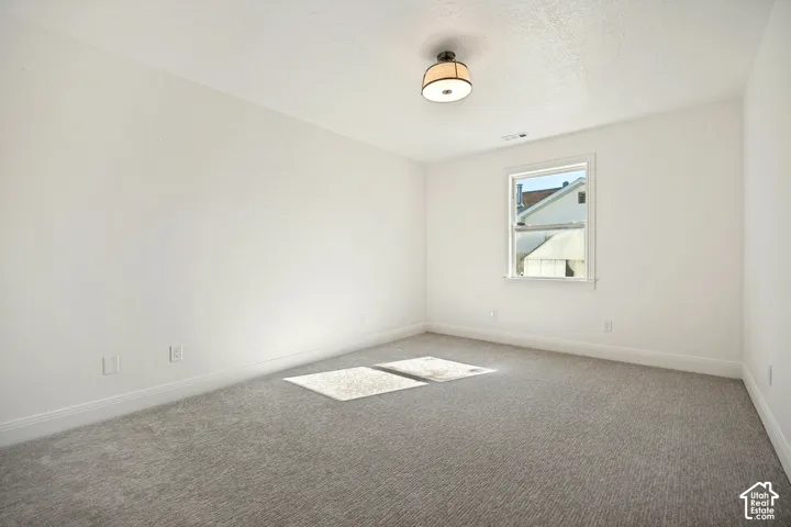 Neutral wall finishes, recessed window, ceiling-mounted lighting fixture, and carpeted flooring