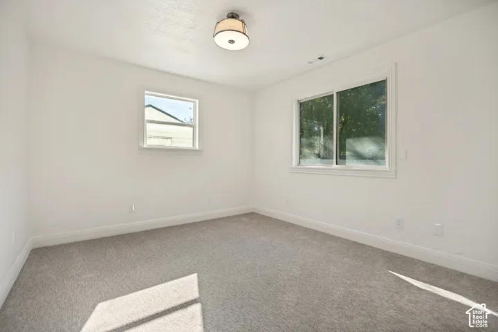 Neutral colored walls, wall-to-wall carpeting, and a semi-flush mount ceiling fixture