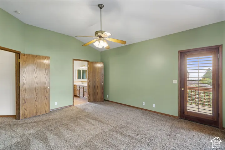 Primary bedroom with Vaulted ceiling with a ceiling fan, carpeted flooring, and a glass-paneled door to an exterior balcony