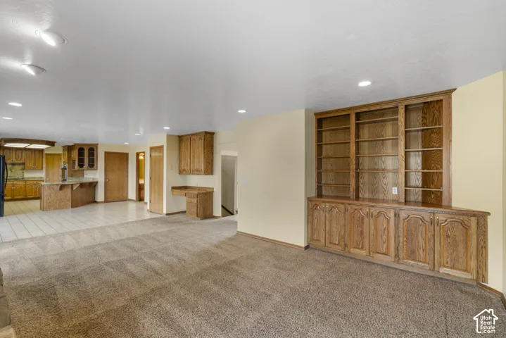 Built-in wood cabinetry and shelving, recessed lighting, and neutral-tone carpeting