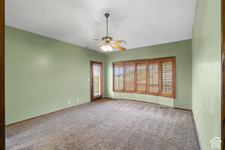 Primary bedroom featuring wall-to-wall carpeting, light green walls, and wood trim