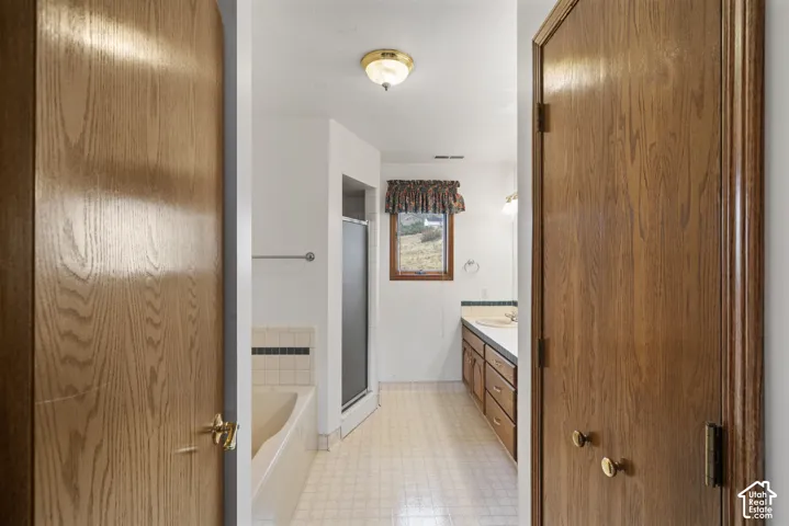 Bathroom featuring a built-in vanity with dual sinks, a bathtub, and a shower enclosure