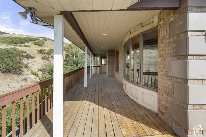 Expansive outdoor deck featuring wood-finish flooring, a covered ceiling, and a wood railing
