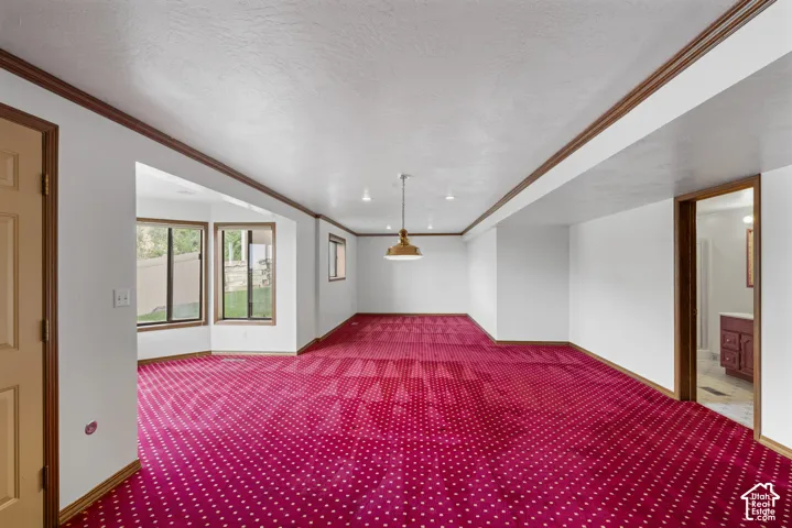Expansive carpeted area with a bay window, recessed lighting, and a suspended light fixture