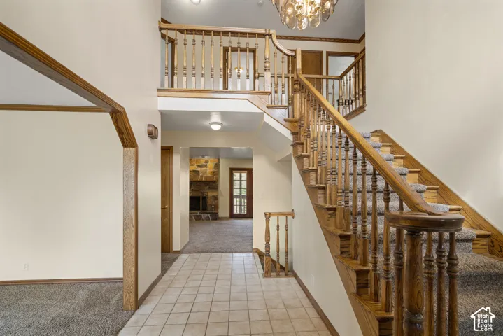 Two-story entry with a wood staircase featuring turned balusters, a tile floor, and a decorative chandelier