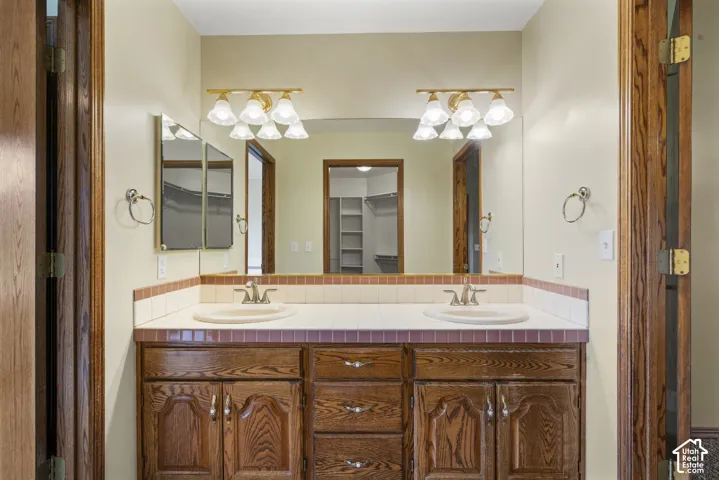 Primary bathroom with Dual vanity with integrated sinks, wood cabinetry, and a tile countertop