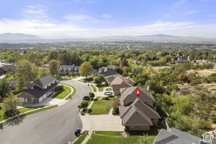Prestigious hilltop estate featuring a striking brick exterior with multiple gables, circular driveway with mature landscaping, and expansive grounds overlooking a sprawling valley vista