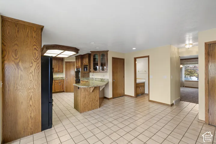 Kitchen featuring wood cabinetry, solid surface countertops, a built-in oven, and tile flooring