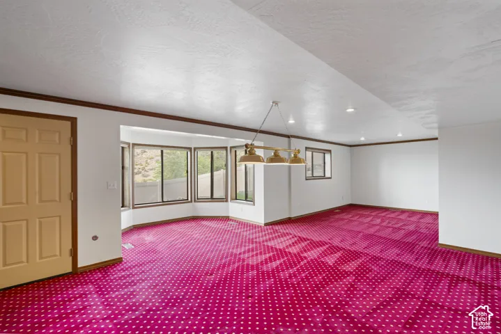 Expansive room featuring a bay window, recessed lighting, and a hanging light fixture