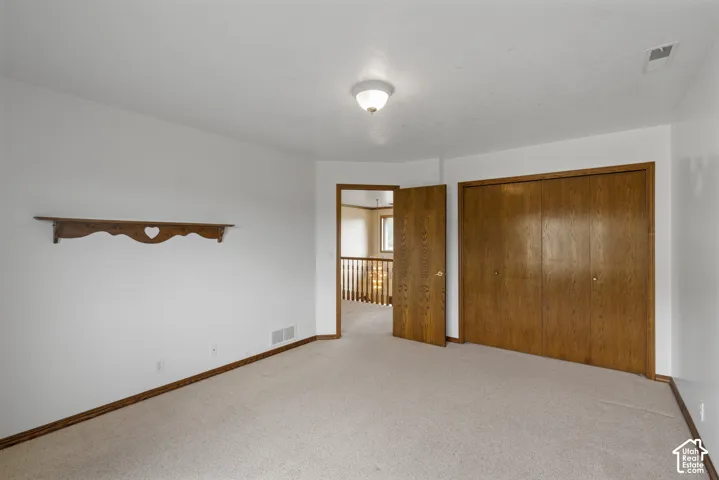 Neutral tone wall paint, neutral tone carpeting, wood-finish trim, wood-finish doors, and a ceiling-mounted light fixture