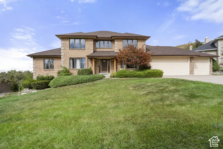 Brick exterior with multiple large windows, a prominent entrance, a two-car garage, and established front landscaping