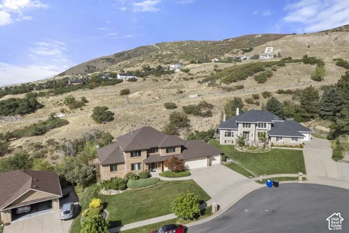 Stunning two-story residence with brick and stone exterior, situated on expansive grounds featuring manicured lawns, mature landscaping, and rolling hillside backdrop