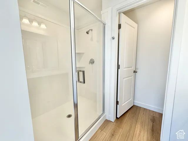 Frameless glass shower enclosure with chrome hardware, integrated shower shelving, and a wall-mounted showerhead
