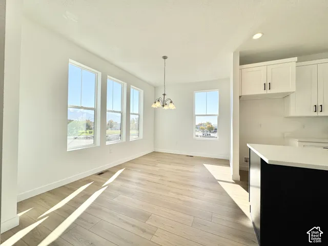 Open-concept dining area with wood-finish flooring, a contemporary chandelier, and multiple windows
