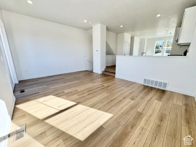 Spacious room featuring wood-finish flooring, recessed lighting, and a half-wall partition